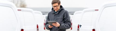 Man with tablet in front of vans
