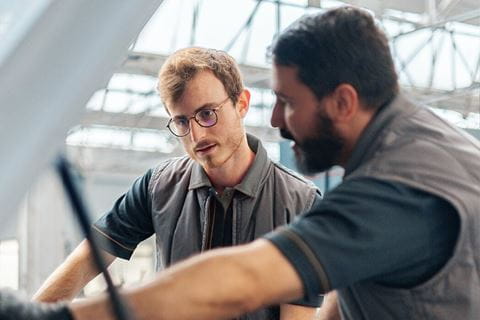 Two men checking the engine of a van