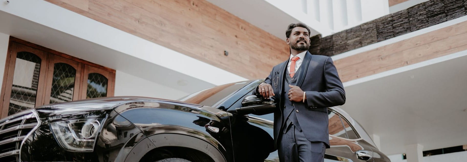 man proudly standing in front of a car