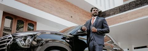 man proudly standing in front of a car