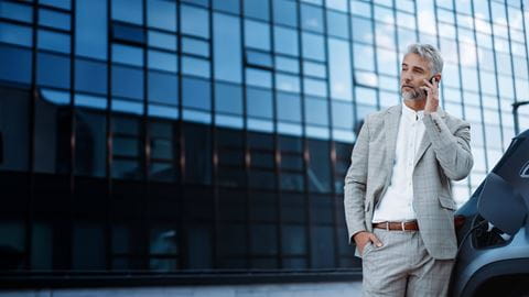 Mann telefoniert während E-Auto lädt